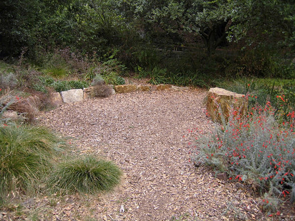 Stone benches and wood chip paving in California native garden. Photo © Michael Thilgen